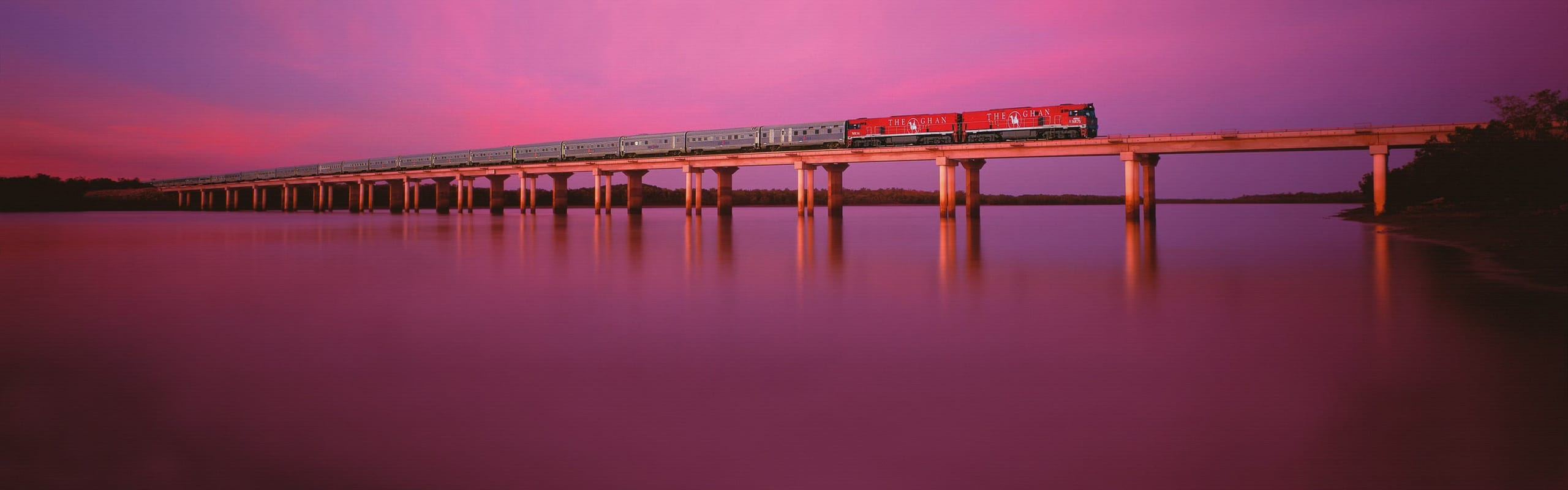 The Ghan fährt im rosafarbenen Abendlicht über die Brücke am Elizabeth River
